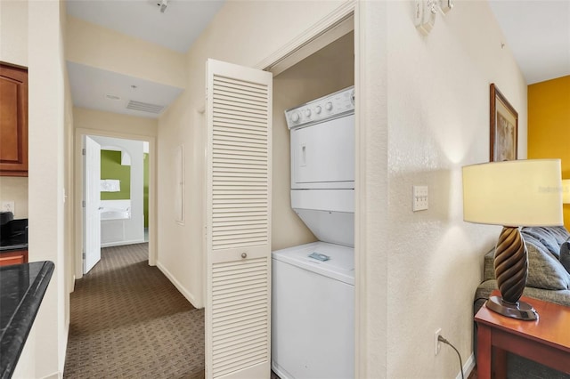 laundry area with baseboards, visible vents, carpet floors, laundry area, and stacked washer / dryer