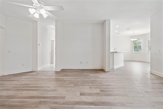 spare room featuring ceiling fan with notable chandelier and light hardwood / wood-style floors