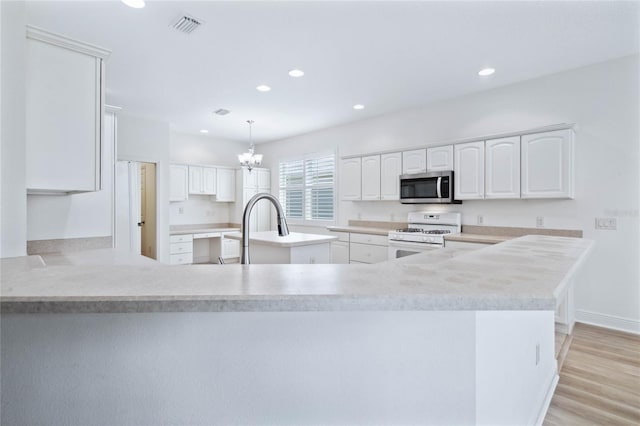 kitchen with white cabinets, white gas range, light hardwood / wood-style flooring, decorative light fixtures, and a notable chandelier