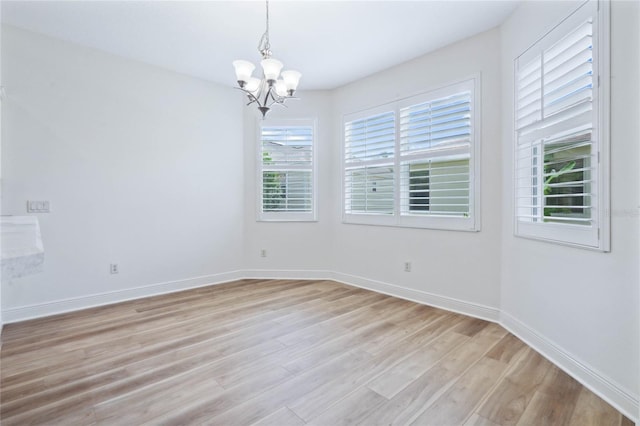 spare room featuring light hardwood / wood-style flooring and a notable chandelier