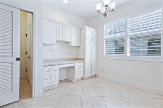 unfurnished office featuring built in desk, a notable chandelier, and light tile patterned floors