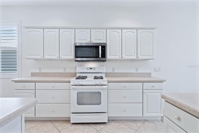 kitchen featuring white range with gas stovetop, white cabinetry, and light tile patterned flooring