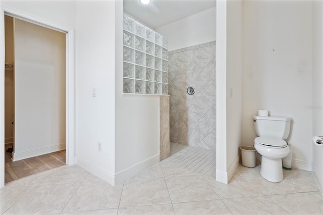 bathroom with tiled shower, toilet, and tile patterned floors