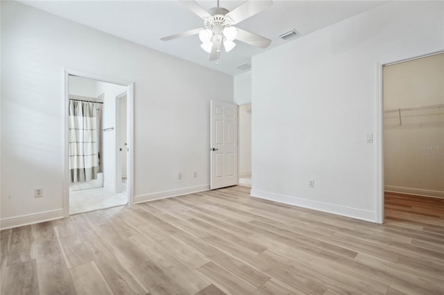 unfurnished bedroom with a closet, ceiling fan, a spacious closet, and light hardwood / wood-style flooring