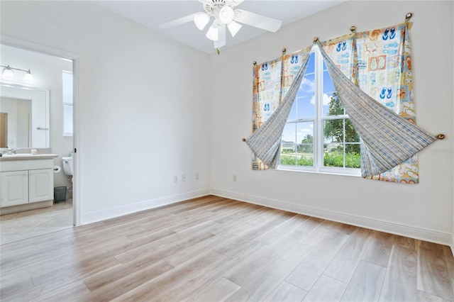 interior space featuring ceiling fan, sink, ensuite bath, and light wood-type flooring