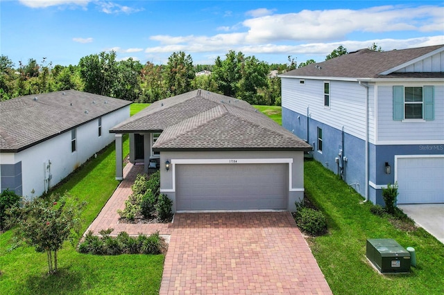 view of front of house featuring stucco siding, an attached garage, decorative driveway, and a front yard