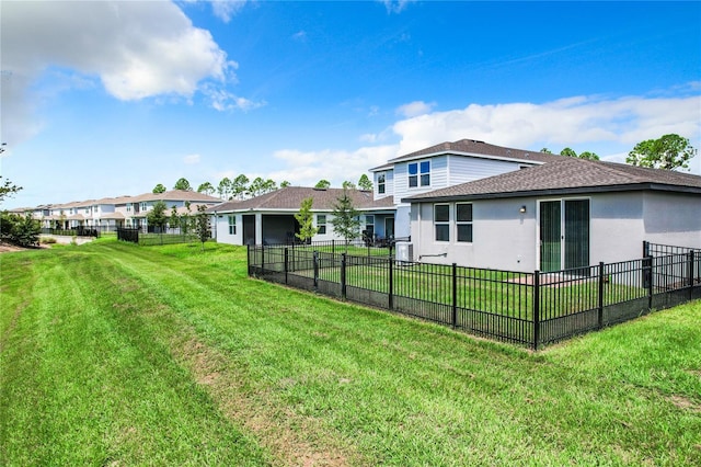 rear view of property featuring a lawn, fence, and stucco siding