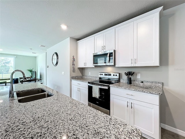 kitchen featuring light stone countertops, visible vents, a sink, stainless steel appliances, and white cabinetry