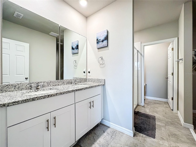 bathroom with double vanity, baseboards, visible vents, and a sink