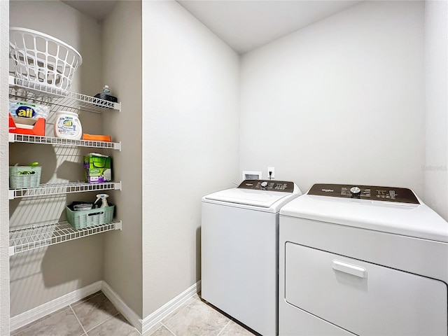 laundry room with baseboards, separate washer and dryer, light tile patterned flooring, and laundry area