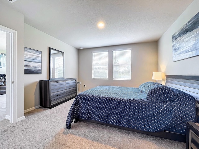 carpeted bedroom featuring baseboards, multiple windows, and a textured ceiling