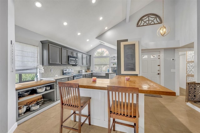 kitchen with gray cabinetry, appliances with stainless steel finishes, a breakfast bar area, pendant lighting, and butcher block counters