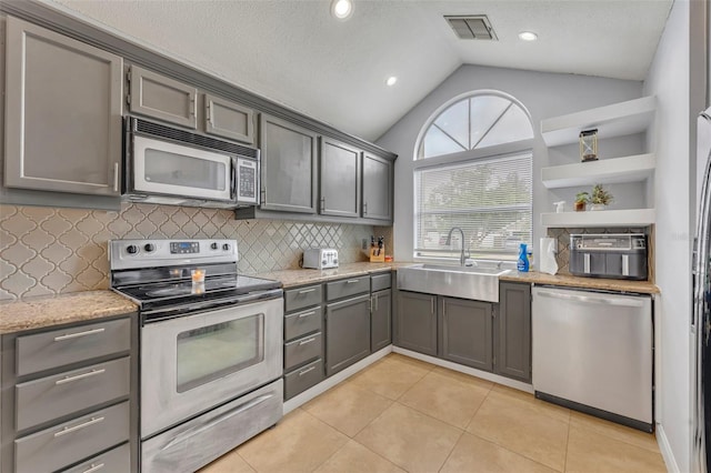 kitchen featuring gray cabinets, appliances with stainless steel finishes, vaulted ceiling, and sink