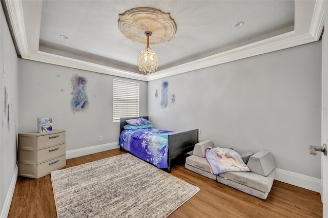 bedroom with a raised ceiling, a textured ceiling, and hardwood / wood-style flooring