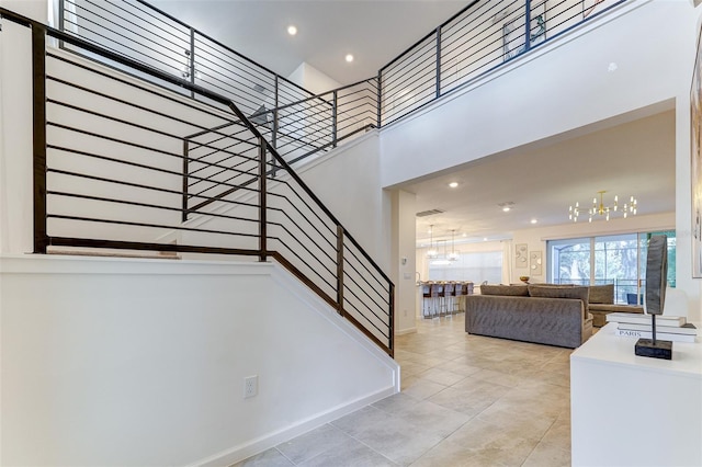 stairs with a towering ceiling and a notable chandelier