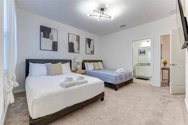 bedroom with a textured ceiling, light colored carpet, and connected bathroom