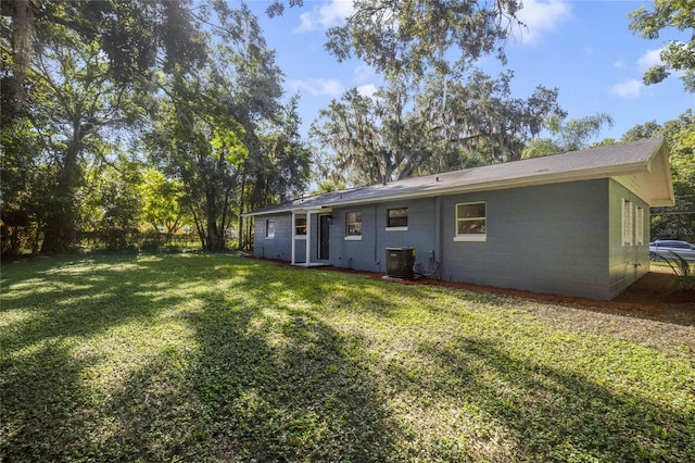 rear view of house featuring central AC and a yard