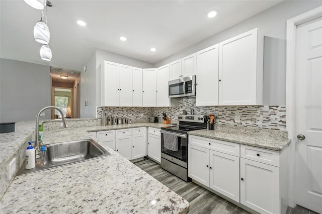 kitchen featuring backsplash, stainless steel appliances, sink, white cabinetry, and light wood-type flooring