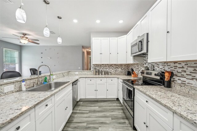 kitchen with stainless steel appliances, light hardwood / wood-style floors, sink, ceiling fan, and tasteful backsplash