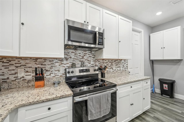 kitchen featuring white cabinets, light stone countertops, stainless steel appliances, and tasteful backsplash