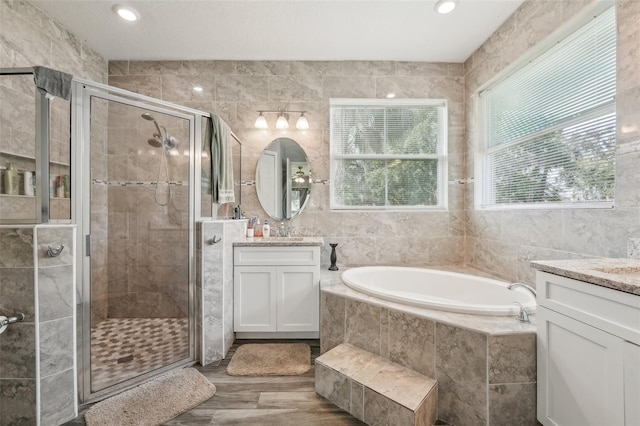 bathroom featuring tile walls, separate shower and tub, and vanity