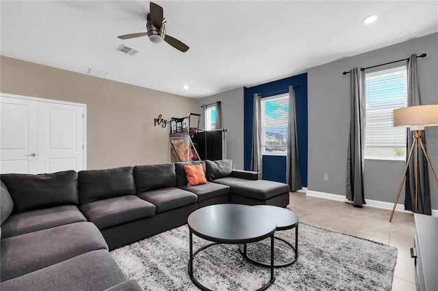 tiled living room with ceiling fan and a textured ceiling