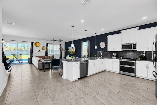 kitchen with stainless steel appliances, sink, kitchen peninsula, ceiling fan, and pendant lighting