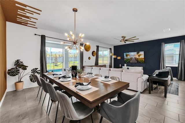 dining area featuring ceiling fan with notable chandelier, plenty of natural light, and light tile patterned flooring