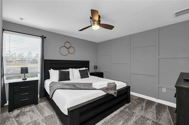 carpeted bedroom featuring ceiling fan and a textured ceiling