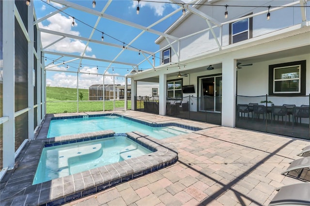 view of pool with an in ground hot tub, a patio, a lawn, glass enclosure, and ceiling fan