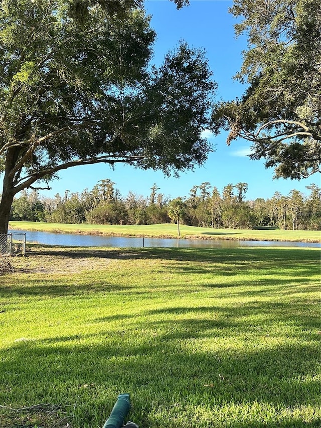 surrounding community with a water view and a lawn