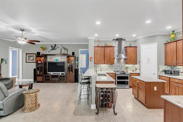 kitchen with a kitchen island, crown molding, ceiling fan, electric stove, and wall chimney range hood