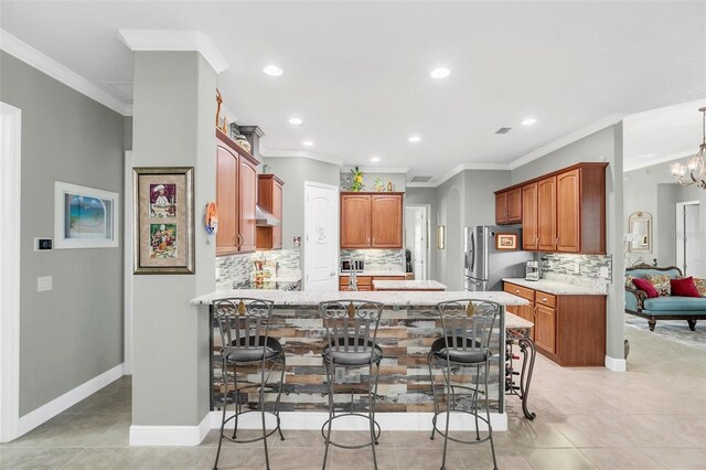 kitchen with stainless steel fridge, a kitchen bar, a chandelier, and crown molding