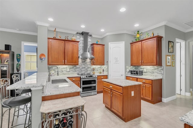 kitchen featuring stainless steel range with electric stovetop, sink, a center island, wall chimney exhaust hood, and a breakfast bar area