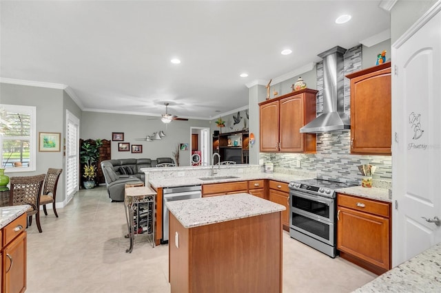 kitchen with a center island, stainless steel appliances, sink, ceiling fan, and ornamental molding