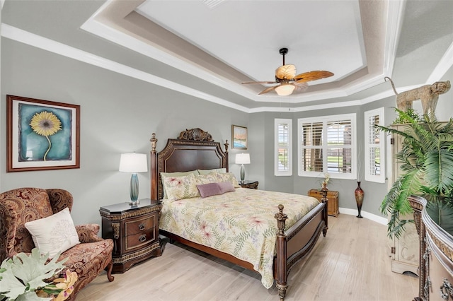 bedroom with ceiling fan, a raised ceiling, light hardwood / wood-style floors, and crown molding