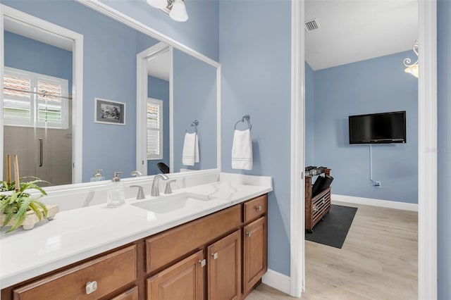 bathroom featuring hardwood / wood-style flooring, a shower with door, and vanity