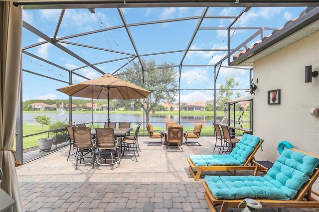 view of patio featuring glass enclosure and a water view