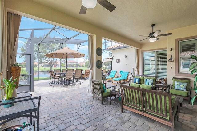 view of patio / terrace featuring a water view, ceiling fan, glass enclosure, and an outdoor hangout area