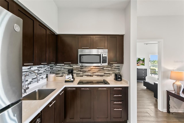 kitchen with dark hardwood / wood-style floors, dark brown cabinets, backsplash, appliances with stainless steel finishes, and sink