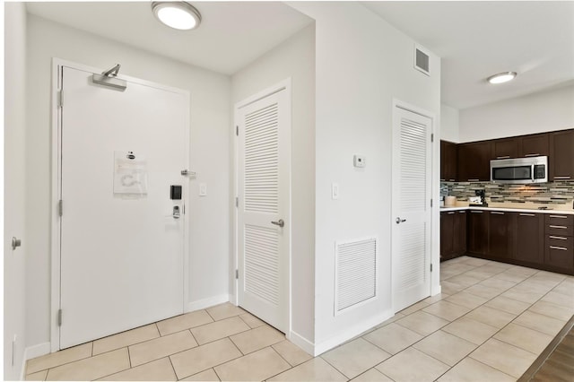 225 Celebration Pl Unit 427, Celebration, FL 34747 - kitchen with stainless steel microwave, dark brown cabinetry, light countertops, and tasteful backsplash