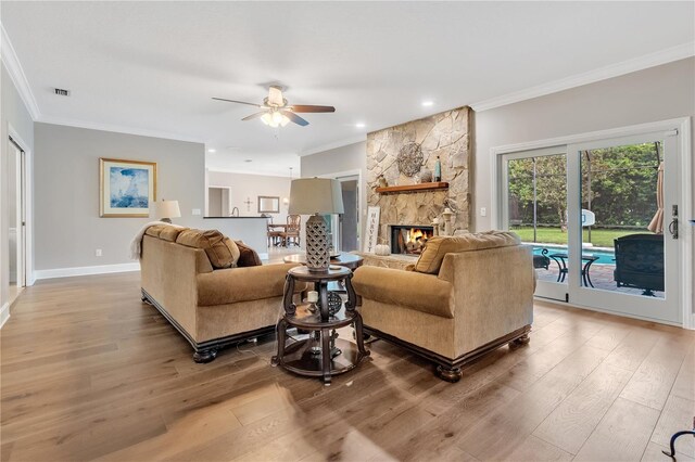 living room featuring a fireplace, hardwood / wood-style floors, ceiling fan, and ornamental molding