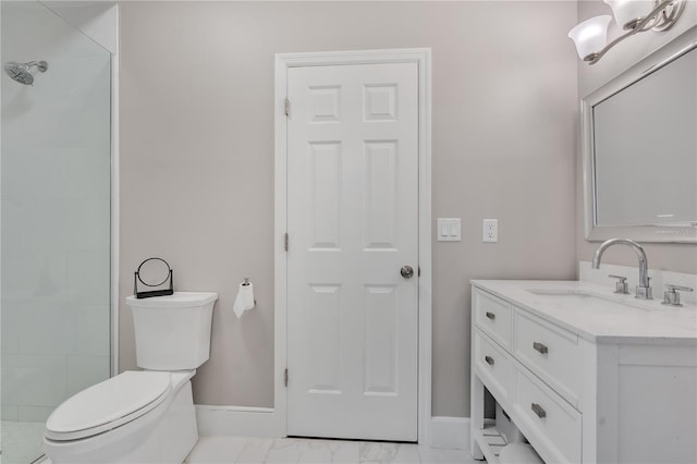 bathroom with a tile shower, vanity, and toilet