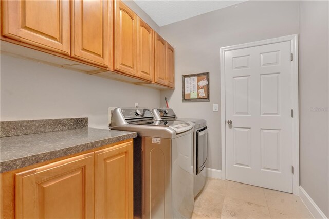 laundry area featuring cabinets, independent washer and dryer, and light tile patterned floors