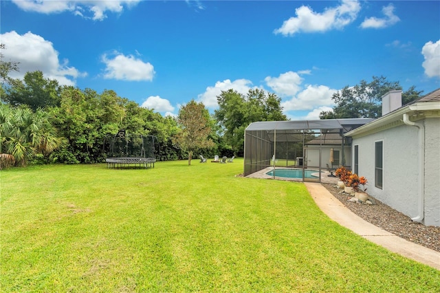 view of yard with glass enclosure and a trampoline