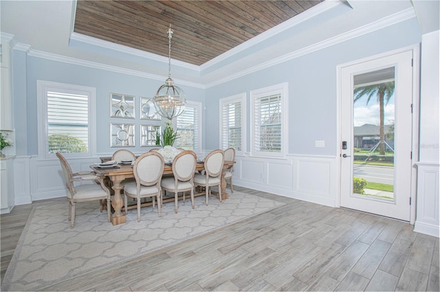 dining area with plenty of natural light, a raised ceiling, and light wood-type flooring