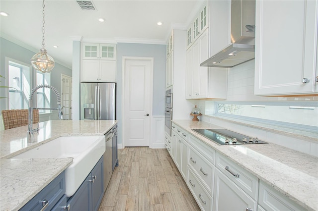 kitchen featuring wall chimney exhaust hood, stainless steel appliances, blue cabinetry, white cabinetry, and hanging light fixtures