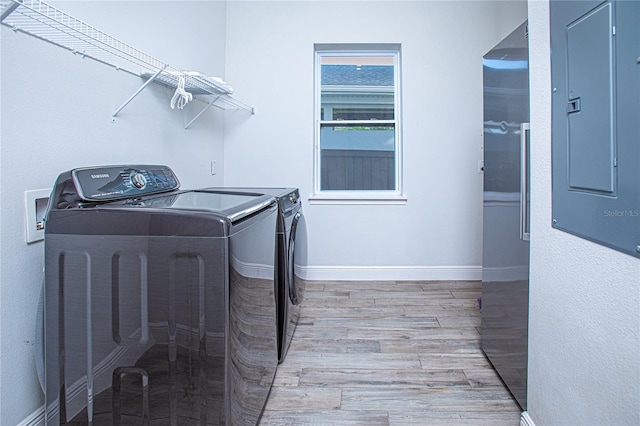 laundry area featuring washer and clothes dryer, electric panel, and light hardwood / wood-style flooring