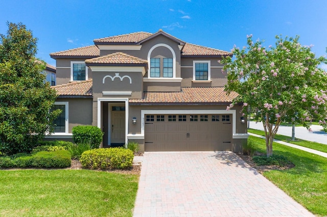 mediterranean / spanish-style home with a garage and a front lawn