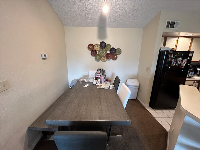 dining area featuring light tile patterned flooring, visible vents, and a textured ceiling